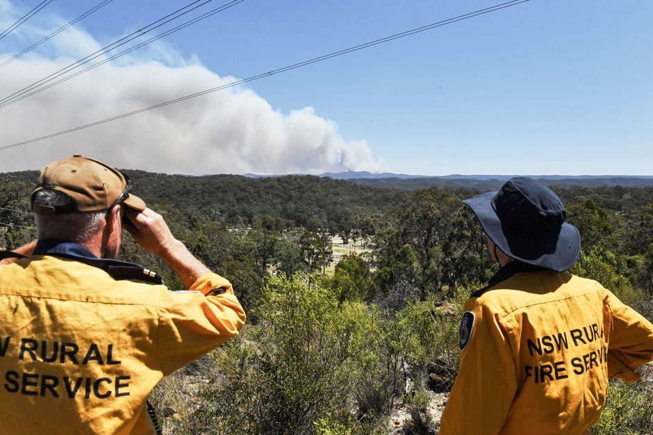 Two members of the Rural Fire Service in New South Wales, Australia monitor a fire in the distance.
