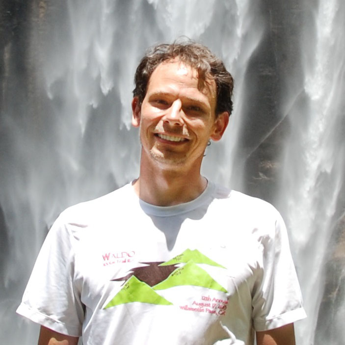 Photograph of Dr. Larry O'Neill in front of a waterfall