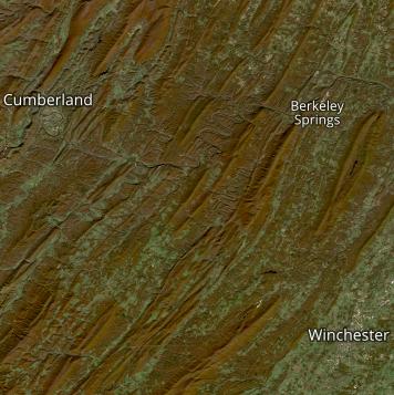 True color satellite image showing fall colors in red among green vegetation in rolling ridges of Appalachia.
