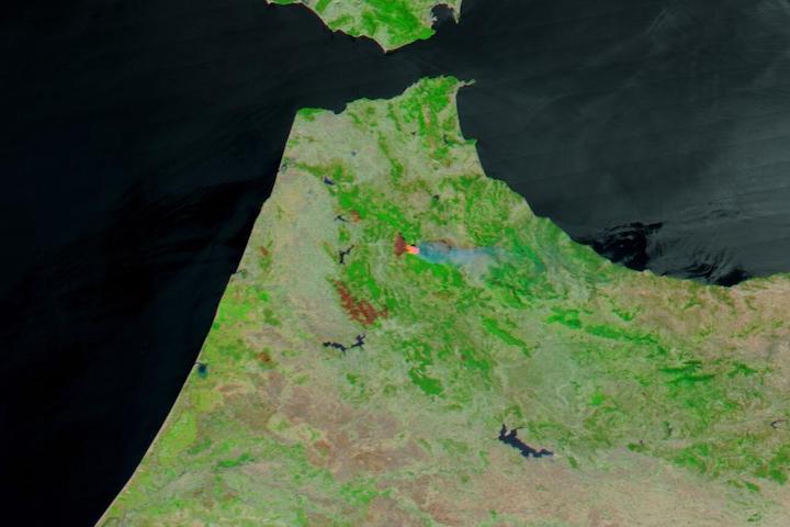 False-color corrected reflectance image of fires and burned areas in northern Morocco on 26 July 2022 from the MODIS instrument aboard the Aqua satellite. The burned areas and fires are shown in red in the center of the image and the surrounding vegetation is green.