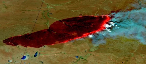 A false color composite image from southeastern Mongolia as seen in FIRMS on April 19, 2022. The burn scar can be seen in dark red, the fire front in bright orange, smoke plumes in light blue, and finally white pyrocumulus clouds just ahead of the fire front.