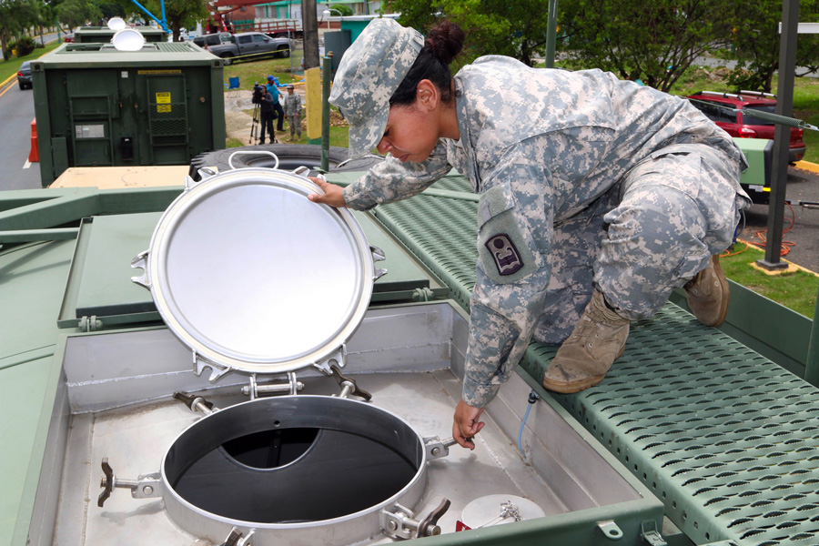 Photograph of a National Guard member checking a portable water tank