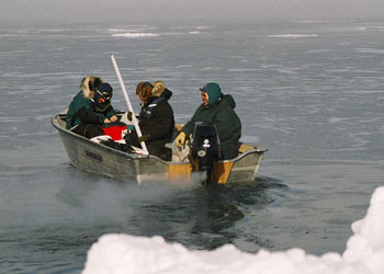 Photograph of researchers boating into a sea ice lead to collect samples