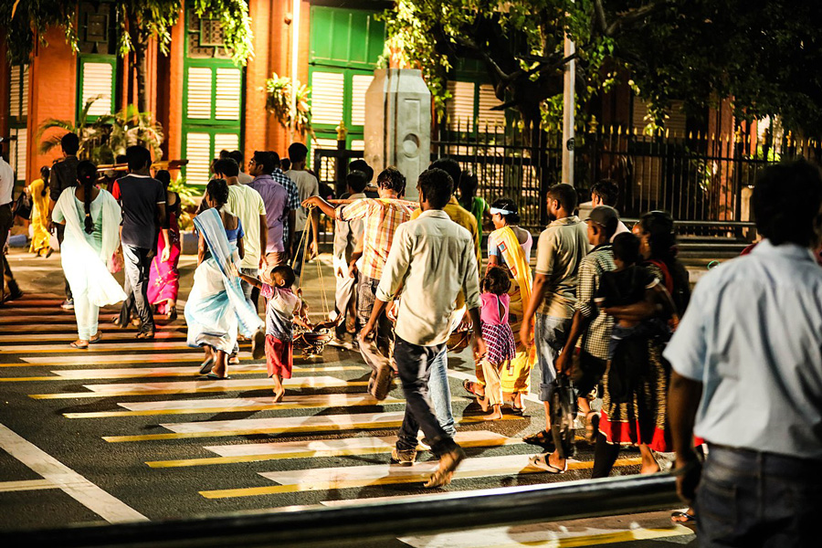 Photograph of Chennai residents in a well-lit crosswalk at night