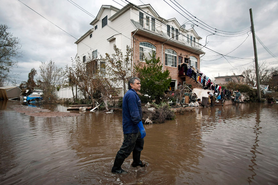 Photograph of a man wading through flooded streets in Staten Island, New York