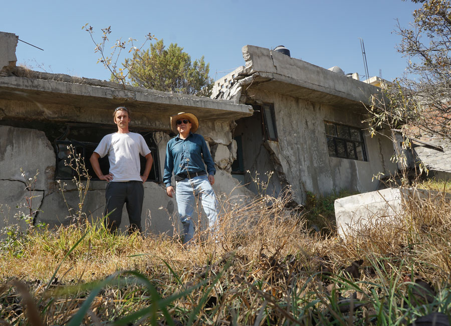 Photograph of two researchers standing in front of a fractured house