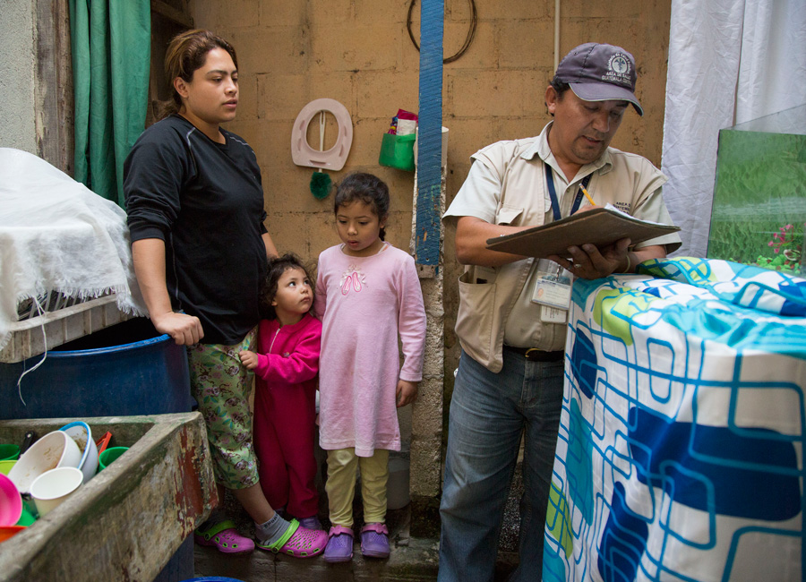 Photograph of a government relief worker checking a family's home in Guatemala