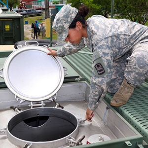 A National Guard member opens a portable military water tank