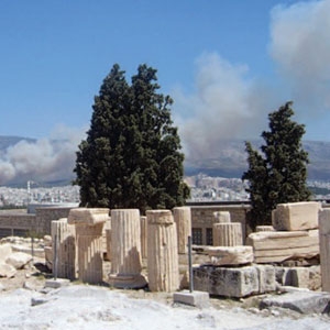 A man walks through the Acropolis while smoke plumes billow from a forest fire near Athens on July 25, 2007.