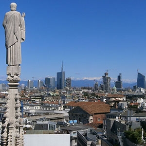 A statue on the spire of Duomo Cathedral overlooks the Milan skyline.