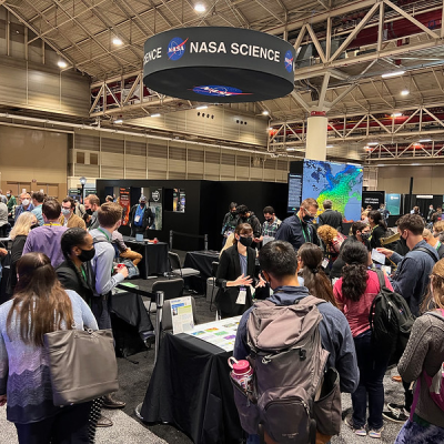 Image of the crowded NASA booth with the NASA Science banner above at the 2021 AGU Fall Meeting
