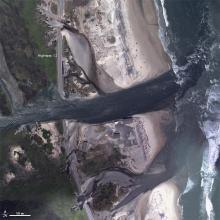 ocean front showing sand dunes cut by storms and water channeling through