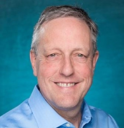 A headshot of Dr. Fred Bingham Professor, University of North Carolina Wilmington, Department of Physics & Physical Oceanography. He is wearing a blue oxford shirt and posing before a turquoise background.