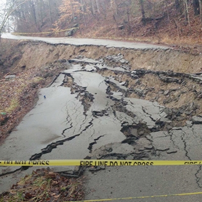 A crumbling asphalt road blocked by Fire Line tape