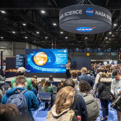 Image of presentation at NASA Hyperwall with lecture attendees in foreground; banner with "NASA Science" hanging from ceiling