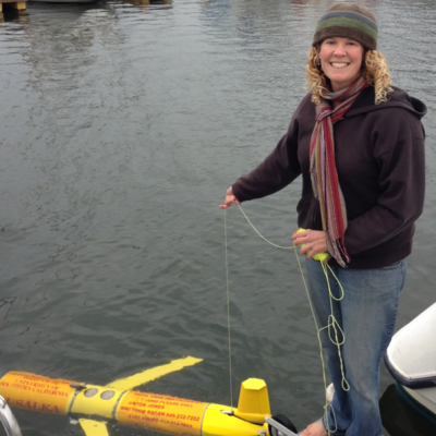 Image of seegers standing on a dock with a yellow glider in the water below her
