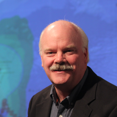 Headshot of dave jones standing in front of a green screen with weather images on it