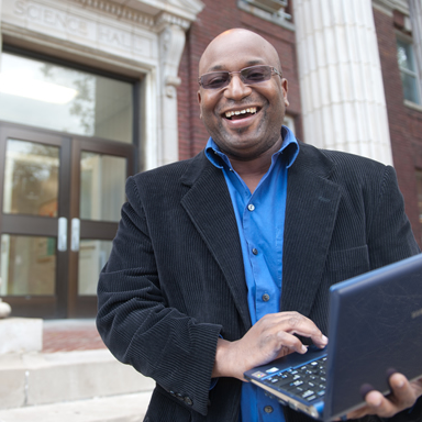 Greg Jenkins standing outside a building holding a computer