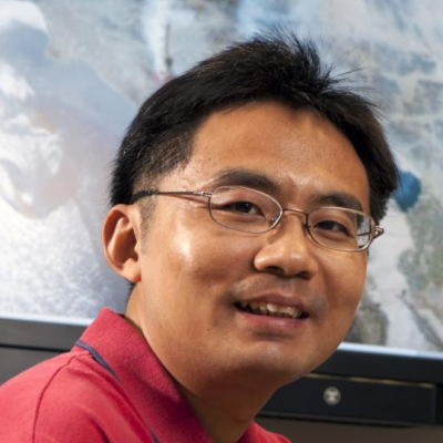 Headshot of Jun Wang sitting at a desk wearing a red polo