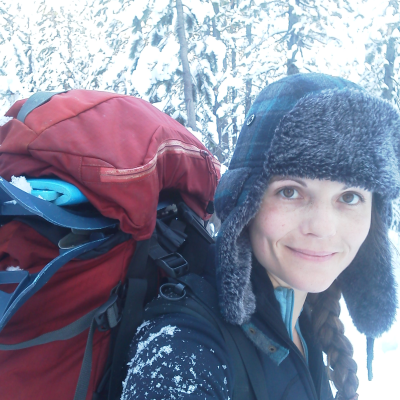 image of Gleason outside in the winter wearing a hat and backpack; snow in background