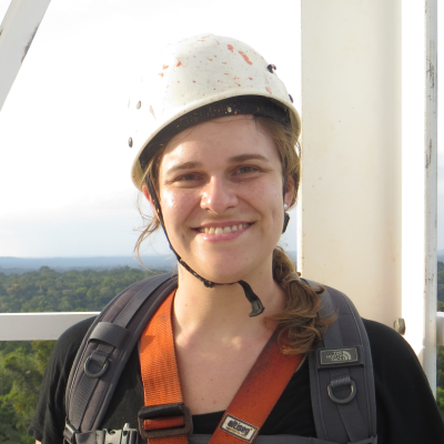 Headshot of albrecht wearing a white hardhat and orange climbing harness standing on a white tower