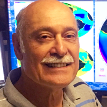 Headshot of Signorini sitting at his desk with a computer monitor behind him