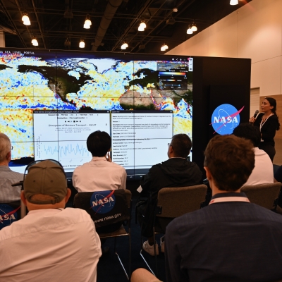 NASA scientist stands in front of the Hyperwall showing Earth observation data