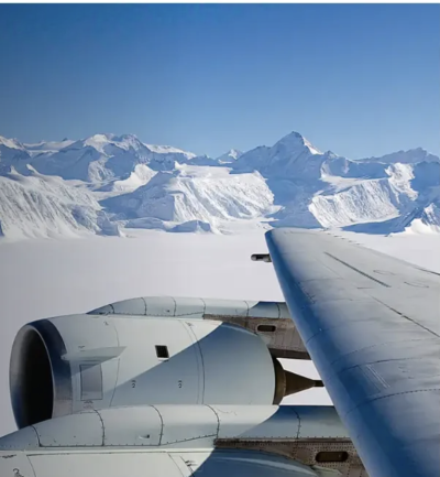 A plane's wing with a snowy mountain in the background