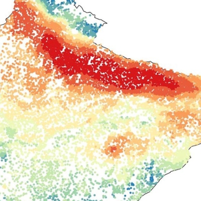The square image shows dots of different colors representing PM2.5 levels across norther India. Blue and green colors in the lower half of the image indicate lower levels of particulates in the air; yellow and red colors in the upper half indicate areas with high levels of pollutants, such as along the foothills of the Himalayas.