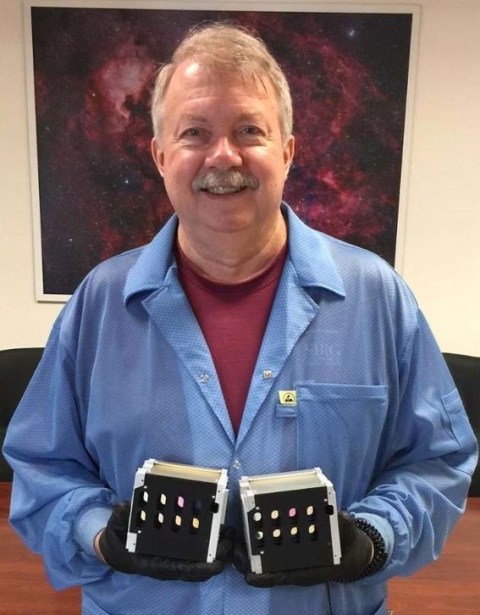 Photograph of Alan Holmes holding both HawkEye flight instruments 