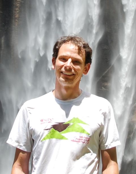 Photograph of Dr. Larry O'Neill in front of a waterfall