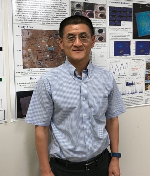 Dr. Zhong Lu standing in front of poster about his research