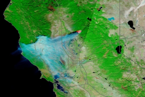 False color image with health vegetation in green, bare soil in brown, and wildfire in red.
