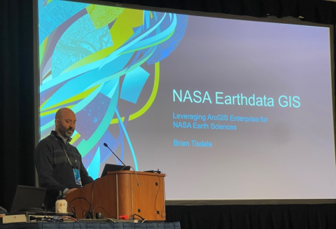 Speaker in front of slide reading "NASA Earthdata GIS"
