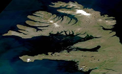 True color mostly clear sky image of northwest Iceland with brown/green land surrounded by dark blue water