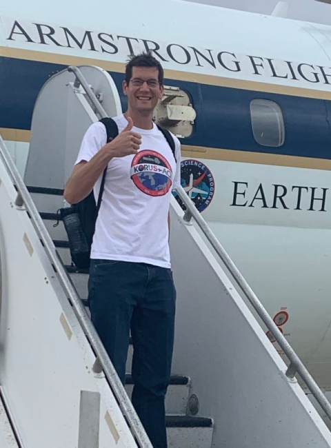 Naval Research Laboratory meteorologist Dr. David Peterson (wearing a white t-shirt and blue jeans) stands on the stairway of a NASA DC-8 after a research flight conducted to sample wildfire smoke in the atmosphere. 