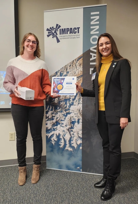 Cerese Albers presents Jeanné le Roux with an IMPACT Award while standing in front of an IMPACT Innovate banner