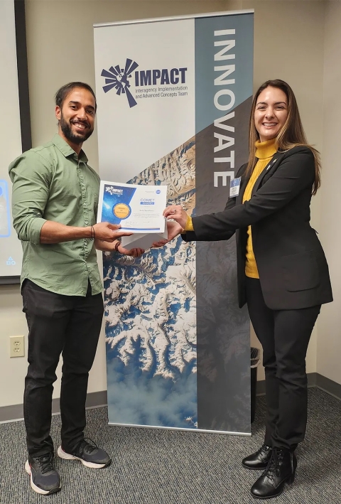 Cerese Albers presents Sid Chaudhary with an IMPACT Award while standing in front of an IMPACT Innovate banner