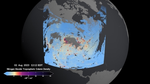 This rectangular image shows a visualization of the TEMPO sensor scanning North America. The globe of Earth is depicted in shades of gray with North America colored in blues, oranges, purples and black. The first-light data shows high levels of nitrogen dioxide--indicated by darker colors--over multiple urban areas across the U.S., Canada, Mexico, and the Caribbean.