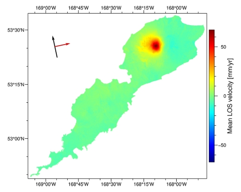 This is an image mapping the elevation change of Okmok volcano and its island. The image is boarded with text showing geographic coordinates and a scale from blue to green to red showing land elevation deflation, stability, and inflation respectively. A majority of the island is colored green to show stable elevation, with a concentrated area of yellow and red in the upper right of the image to show inflation in the caldera.