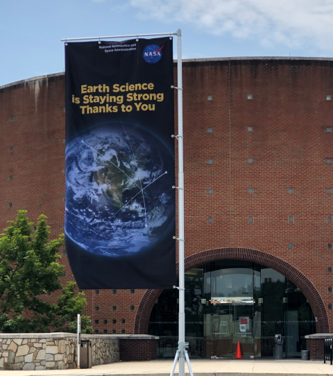 Image of flag outside Goddard Building 32 with words Earth Science is Staying Strong Thanks to You over an image of Earth.
