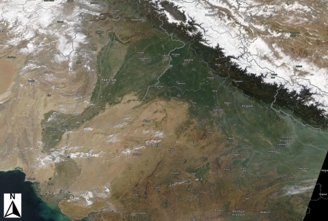 Satellite image of Asia showing the snow-capped Himalayas in the upper right with a greenish strip running from northeast to southwest indicating the path of the Indus River through Pakistan and into the Arabian Sea.