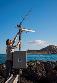 Image of Dr. Philip Thompson adjusting a solar panel on a tide gauge.