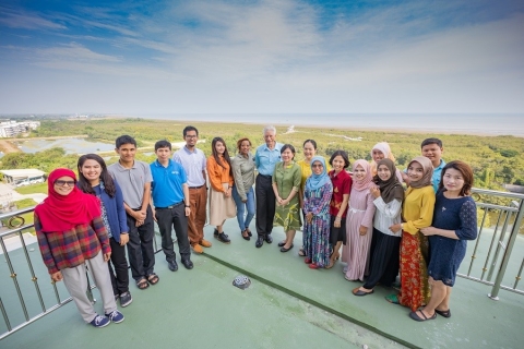 Image of Dr. McNeil standing with his students on a balconey overlooking the Gulf of Thailand.
