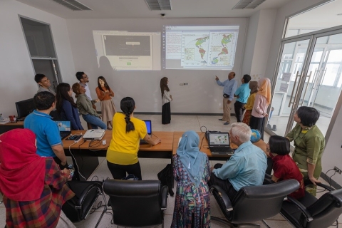 Image showing Dr. McNeil and his students analyzing data projected onto a wall of a classroom.