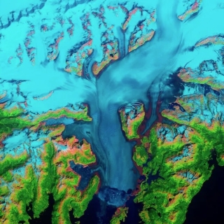 Satellite image of Columbia Glacier, Alaska, with blue glacier amidst green landmass