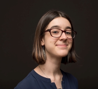 Headshot of Sara in a formal studio pose with a black background.