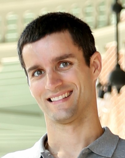 Headshot of Dr. Brian Barnes wearing an open collar shirt and standing in front of a sunny outdoor area.